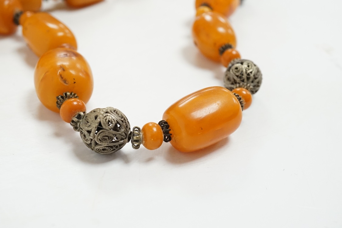 A single strand amber bead necklace, with filigree metal spacers, 48cm, gross 84 grams, together with a group of loose graduated simulated cherry amber beads, gross weight 117 grams.